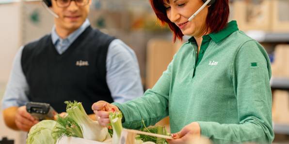 Жена касиер продавач подрежда плод и зеленчук под погледа на мениджър филиал