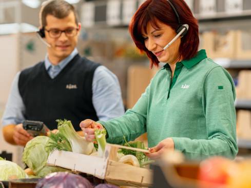Жена касиер продавач подрежда плод и зеленчук под погледа на мениджър филиал