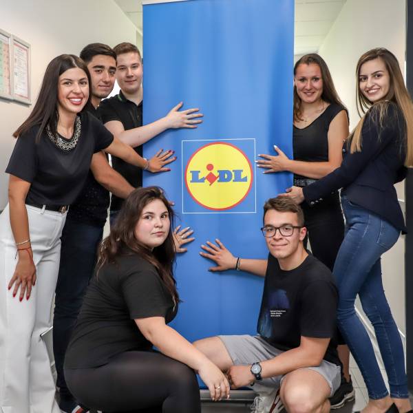 Седем студенти от стажантската програма на Лидл България през 2022 позират до банер с логото на компанията